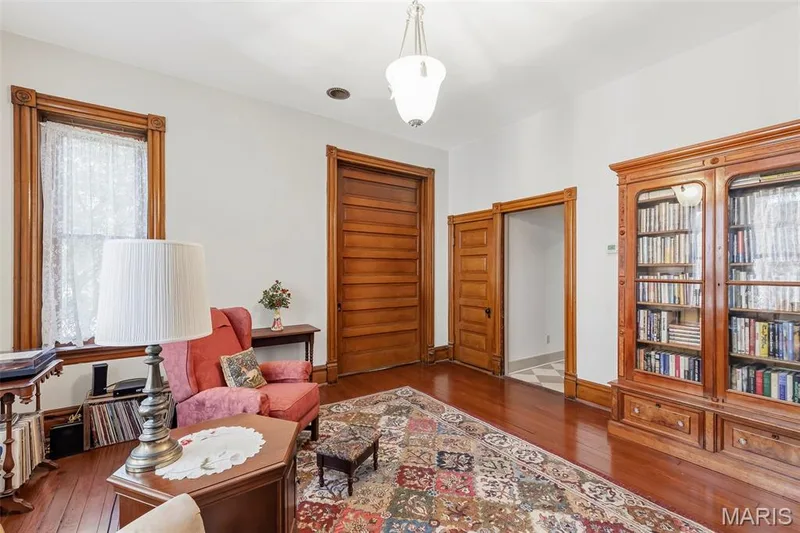 Wood-finish flooring, natural wood trim, built-in wooden cabinetry, pocket door, and pendant light fixture — 711 N 5th Street, St Charles, MO 63301