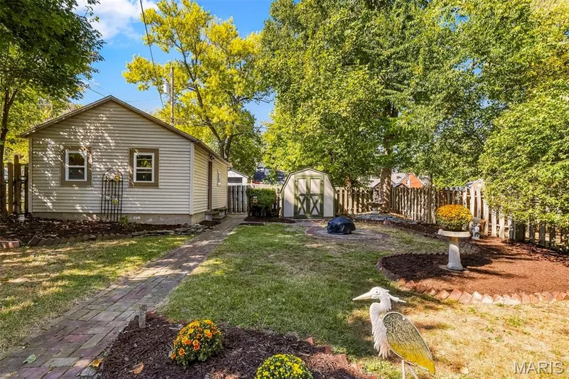 Backyard featuring a detached outbuilding, a secondary storage shed, a brick paver walkway, and perimeter wood fencing — 711 N 5th Street, St Charles, MO 63301
