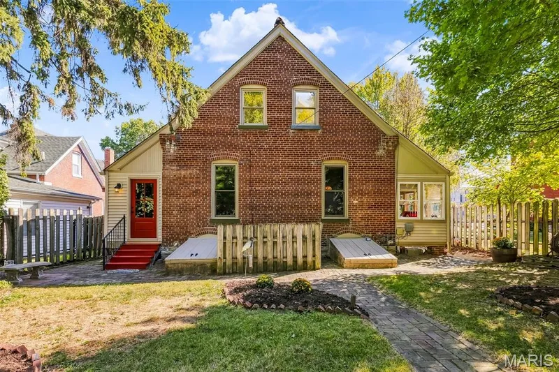 Brick exterior featuring a gabled roofline, dual cellar bulkhead entrances, and a brick paver walkway — 711 N 5th Street, St Charles, MO 63301