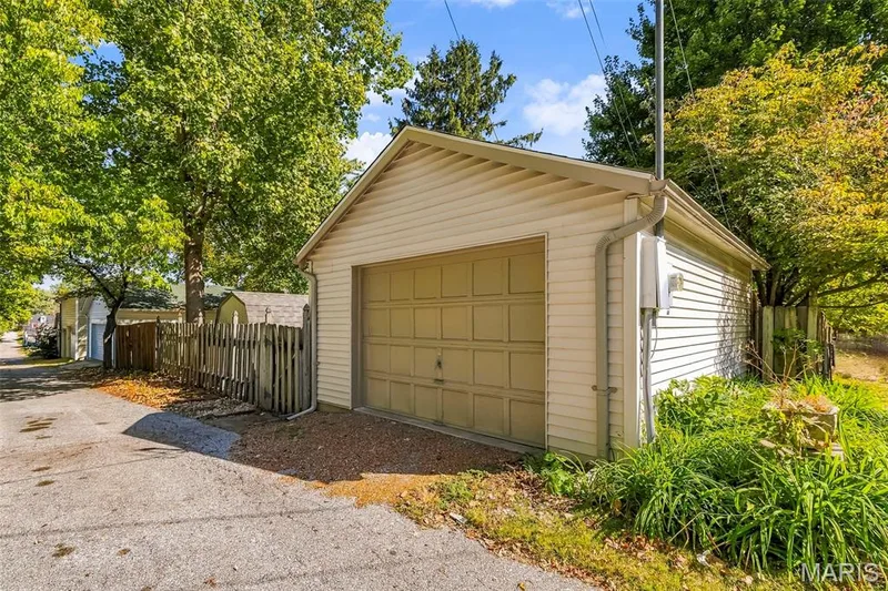 Detached garage with horizontal vinyl siding, asphalt shingle roof, and a sectional overhead door — 711 N 5th Street, St Charles, MO 63301