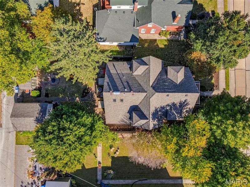 Aerial perspective of a detached residential property featuring a pitched shingle roof, a detached garage structure, paved walkways, and mature landscaping on a tree-lined lot — 711 N 5th Street, St Charles, MO 63301
