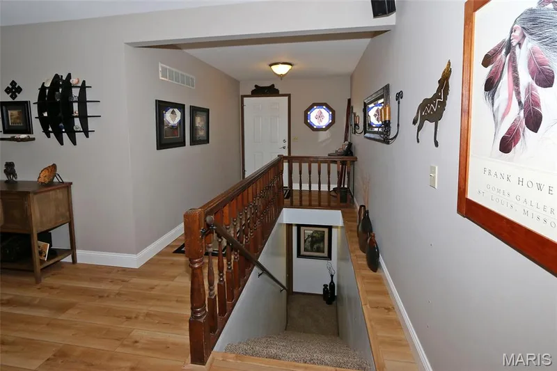 Wood-finish flooring, white trim, and a wood banister with traditional spindles — 1738 Sun Drop Drive, St Charles, MO 63303