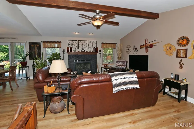 Vaulted ceiling featuring exposed wood beams, wood-finish flooring, and a black brick fireplace — 1738 Sun Drop Drive, St Charles, MO 63303