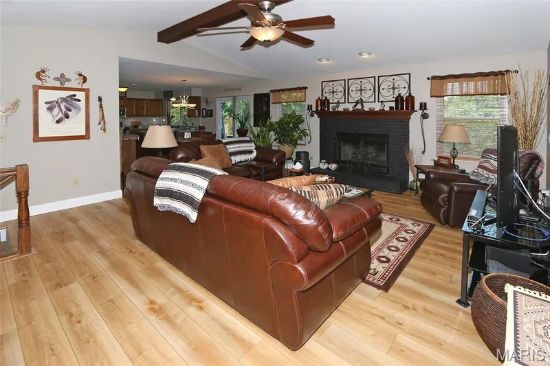 Wood-finish flooring throughout, featuring a black brick fireplace with a wood mantel — 1738 Sun Drop Drive, St Charles, MO 63303