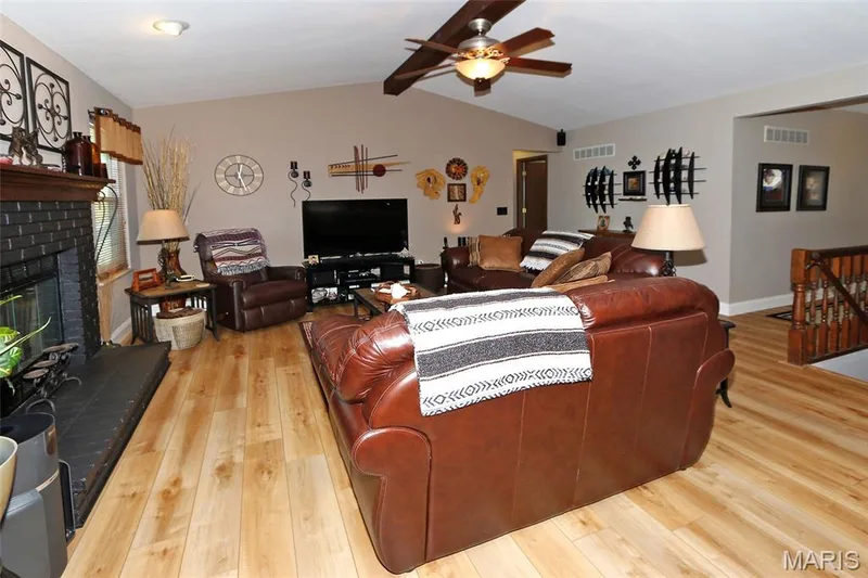 Vaulted ceilings, wood-finish flooring, and a fireplace with a black brick surround — 1738 Sun Drop Drive, St Charles, MO 63303