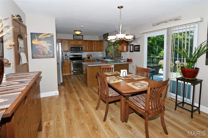 Hardwood-finish flooring throughout, kitchen with wood cabinetry and stainless steel appliances, and a sliding glass door offering outdoor access — 1738 Sun Drop Drive, St Charles, MO 63303