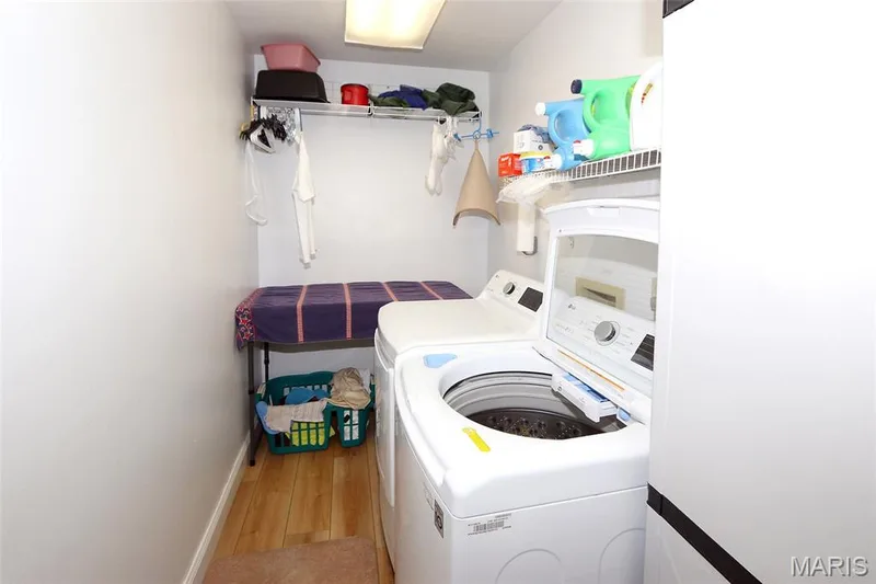 Laundry area featuring wood-finish flooring, overhead wire shelving, and a fluorescent ceiling light fixture — 1738 Sun Drop Drive, St Charles, MO 63303