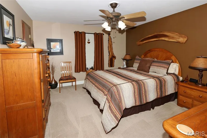 Carpeted room with a ceiling fan light fixture, wood-finish door, and window with solid curtains — 1738 Sun Drop Drive, St Charles, MO 63303