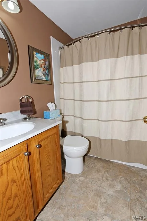 Single vanity with wood-finish cabinetry, integrated sink, and light-toned countertop — 1738 Sun Drop Drive, St Charles, MO 63303