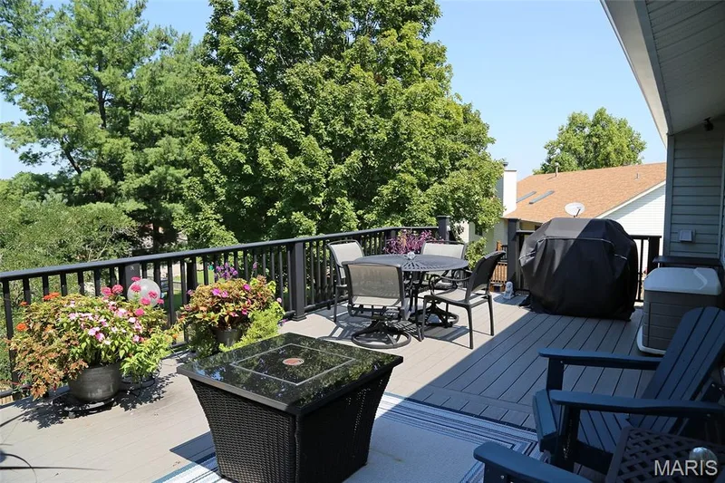 Expansive deck featuring composite decking, black railing, and mature trees as a backdrop — 1738 Sun Drop Drive, St Charles, MO 63303