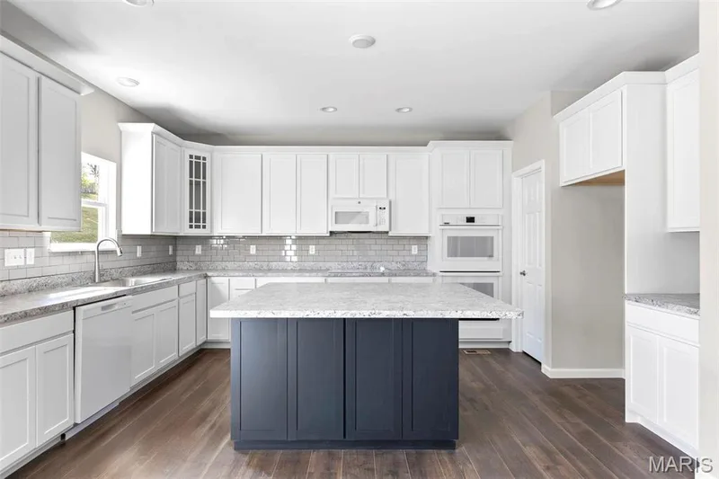 Kitchen with dark wood-type flooring, white appliances, sink, and white cabinets — 2 Hermitage II at Elm Crossing, St Charles, MO 63301