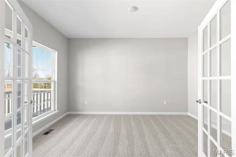 Empty room featuring french doors and light colored carpet — 2 Hermitage II at Elm Crossing, St Charles, MO 63301