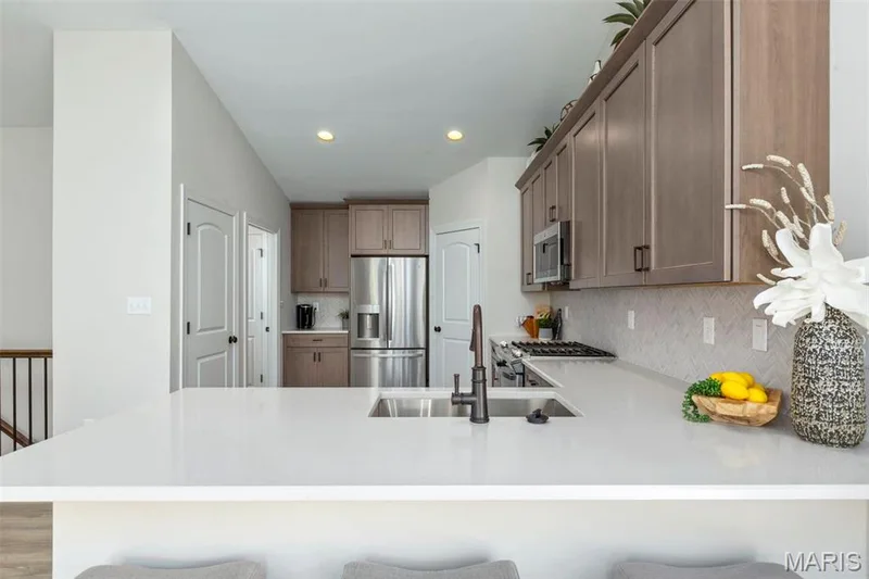 Kitchen featuring a breakfast bar, kitchen peninsula, and appliances with stainless steel finishes — 2 Hickory at Elm Crossing, St Charles, MO 63301
