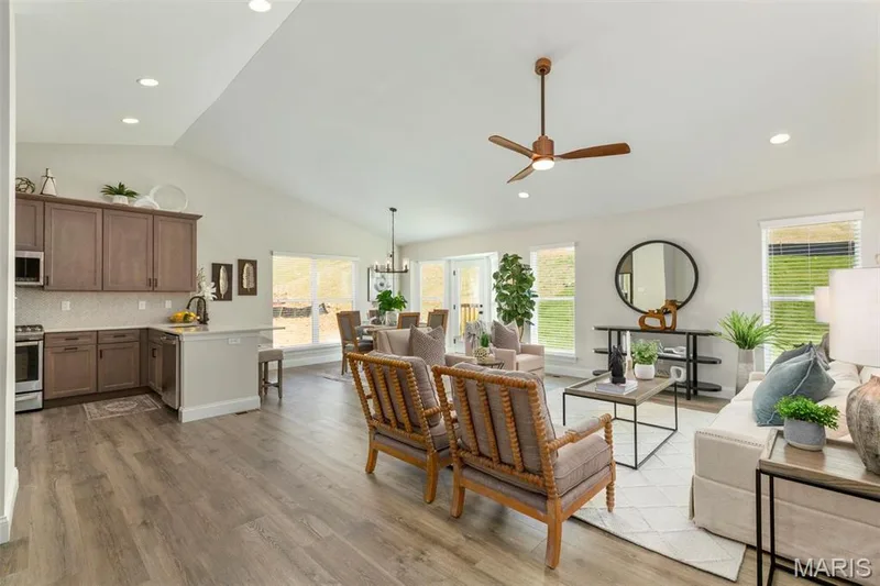 Living room with light hardwood / wood-style flooring, vaulted ceiling, ceiling fan with notable chandelier, and sink — 2 Hickory at Elm Crossing, St Charles, MO 63301