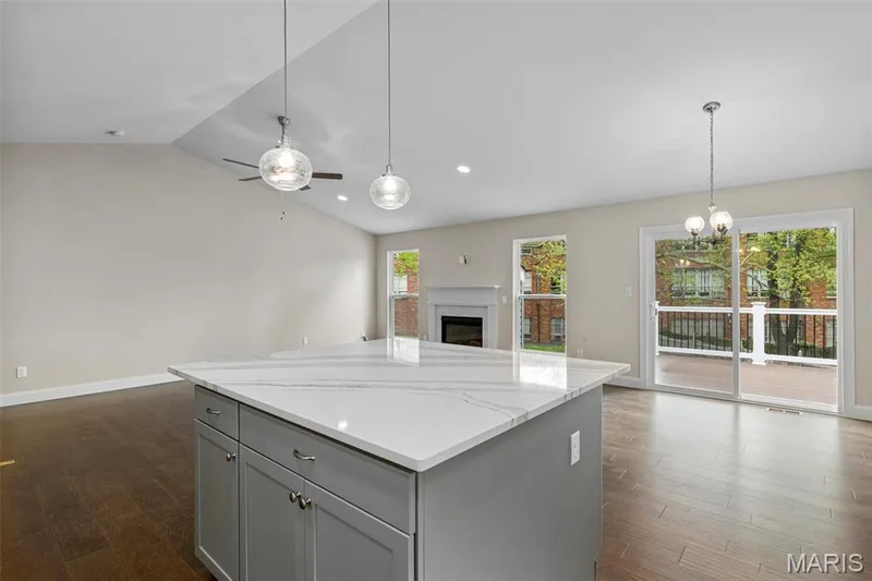 Kitchen with lofted ceiling, plenty of natural light, dark hardwood / wood-style floors, and gray cabinetry — 2 Maple at Elm Crossing, St Charles, MO 63301