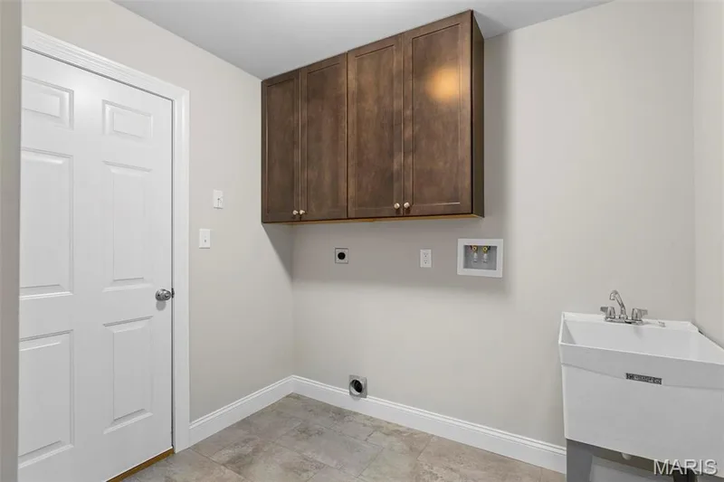 Laundry room featuring cabinets, electric dryer hookup, hookup for a washing machine, and sink — 2 Maple at Elm Crossing, St Charles, MO 63301