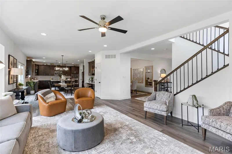 Living room with ceiling fan with notable chandelier and dark hardwood / wood-style floors — 2 Nottingham at Elm Crossing, St Charles, MO 63301