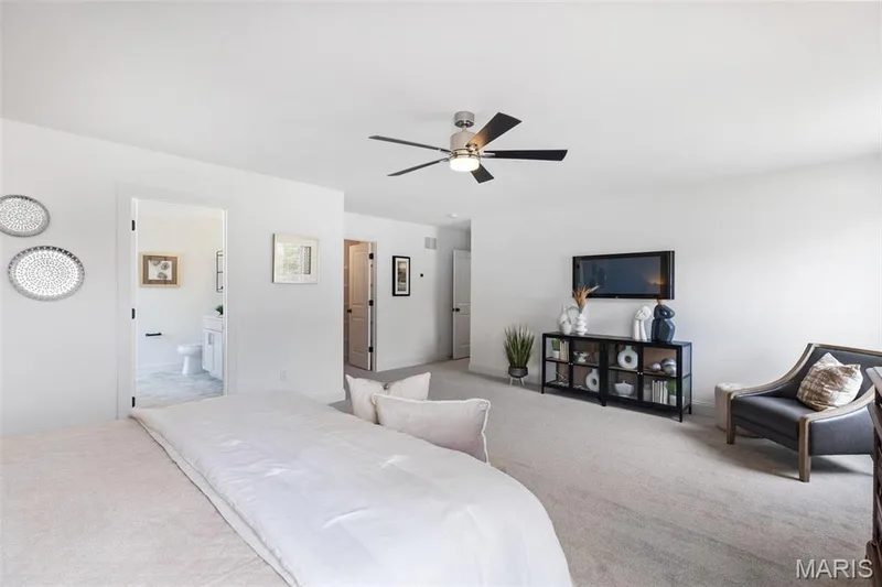 Carpeted bedroom featuring ceiling fan and ensuite bath — 2 Nottingham at Elm Crossing, St Charles, MO 63301