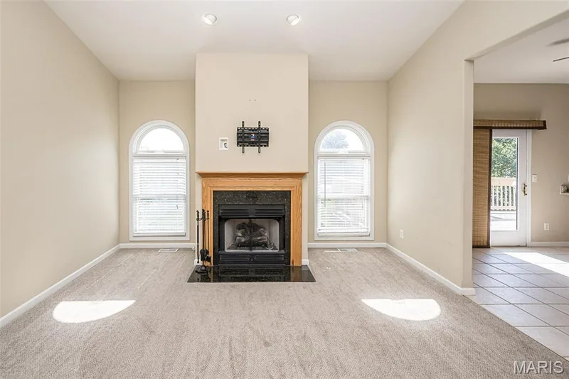 The gas fireplace is the focal point of the Great Room and paired with arch windows framing the space. — 84 Reuben Court, O'Fallon, MO 63376
