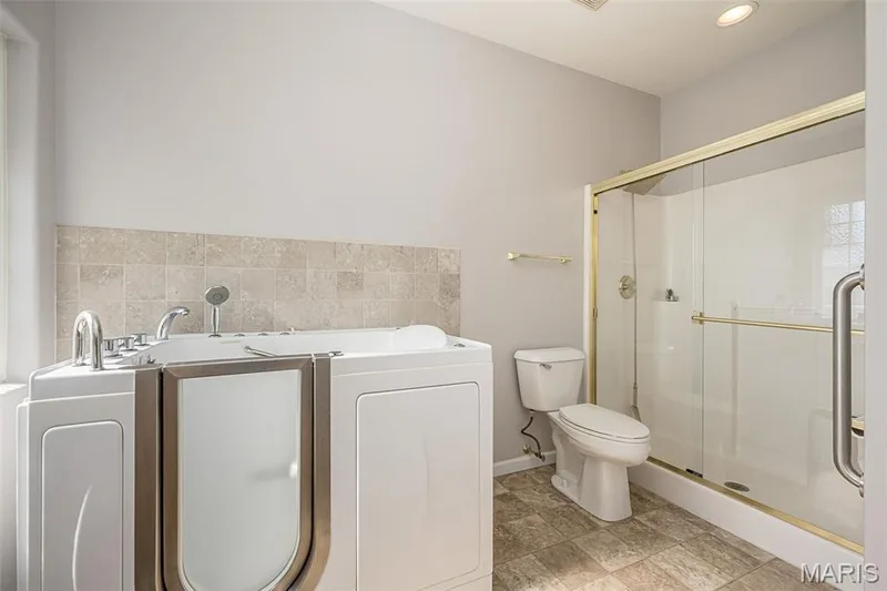 The Primary Bath features a walk-in accessible bath and large walk-in shower.  The tb can easily be removed for a conventional tub arrangement. — 84 Reuben Court, O'Fallon, MO 63376