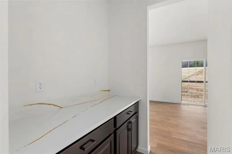 Bar featuring dark brown cabinetry, light hardwood / wood-style flooring, and light stone counters — 2 Sequoia at Elm Crossing, St Charles, MO 63301