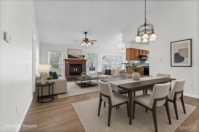 Vaulted ceilings with a ceiling fan, brick fireplace, wood-finish flooring, and a kitchen with wood cabinetry — 2006 Chapel Hill Crossing, St Peters, MO 63376