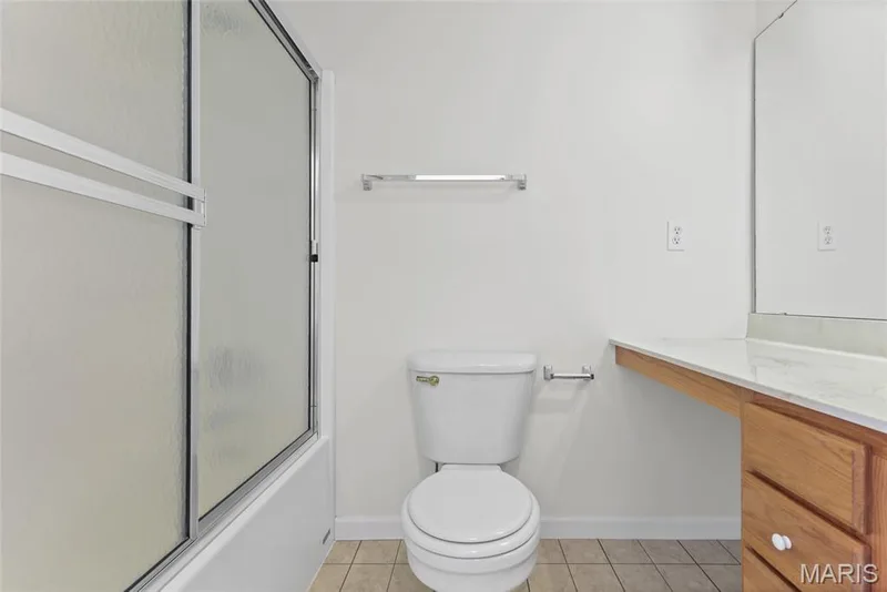 Bathtub with sliding shower doors, tile flooring, and a vanity with a countertop and built-in mirror — 2006 Chapel Hill Crossing, St Peters, MO 63376