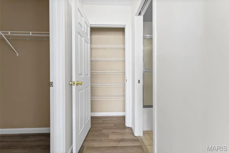 Hallway with wood-finish flooring, white panel doors, and a built-in shelving unit — 2006 Chapel Hill Crossing, St Peters, MO 63376