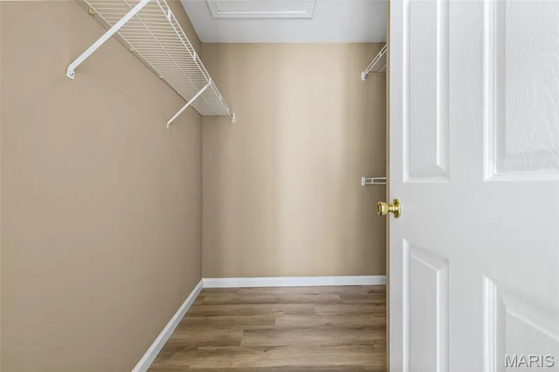 Walk-in closet featuring wire shelving, wood-finish flooring, and a panel door with brass hardware — 2006 Chapel Hill Crossing, St Peters, MO 63376