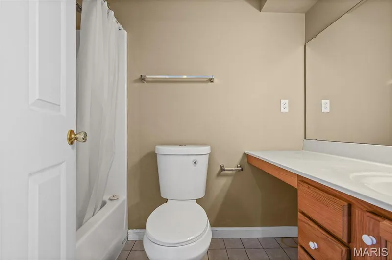 White paneled door, built-in bathtub, toilet, wood-finish vanity with integrated sink, and a large wall-mounted mirror — 2006 Chapel Hill Crossing, St Peters, MO 63376