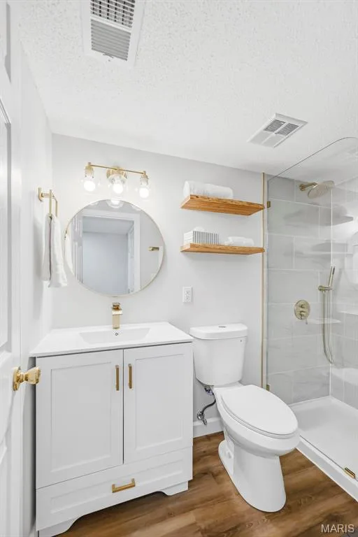 White vanity with an integrated sink, gold-tone fixtures, wood-finish flooring, and a glass-enclosed shower with subway tile — 1410 Heritage Landing #106, St Charles, MO 63303
