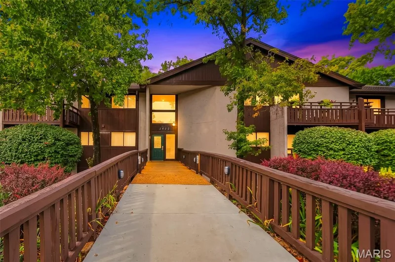 Front elevation featuring a walkway with wood railings and mature landscaping — 1410 Heritage Landing #106, St Charles, MO 63303