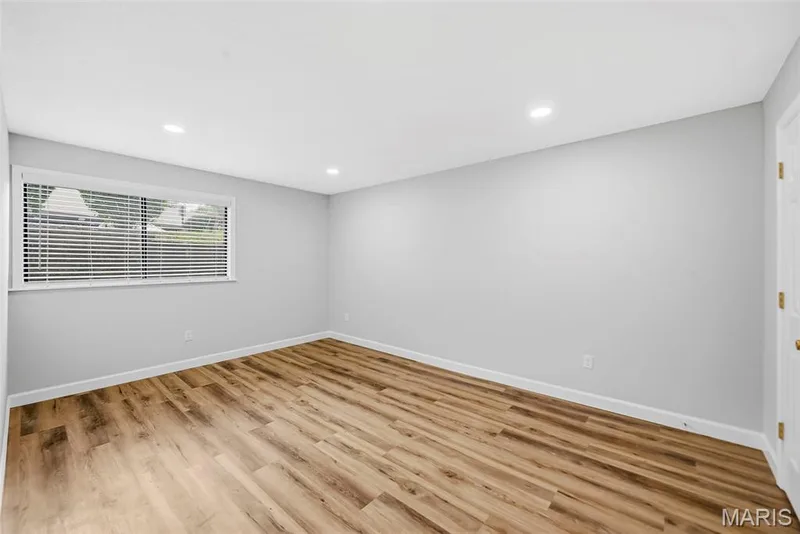 Recessed lighting illuminates the room, featuring wood-finish flooring and light gray walls — 1410 Heritage Landing #106, St Charles, MO 63303