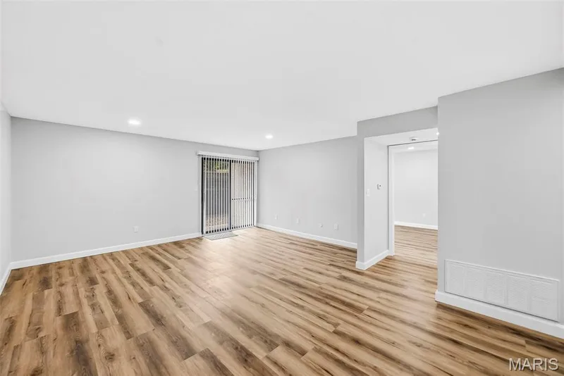 Wood-finish flooring throughout, recessed lighting, neutral wall tones, sliding glass door, and a wide entryway — 1410 Heritage Landing #106, St Charles, MO 63303