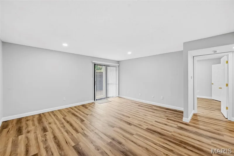 Recessed ceiling lighting, light gray wall finishes, wood-finish flooring, sliding glass door, and white interior door — 1410 Heritage Landing #106, St Charles, MO 63303