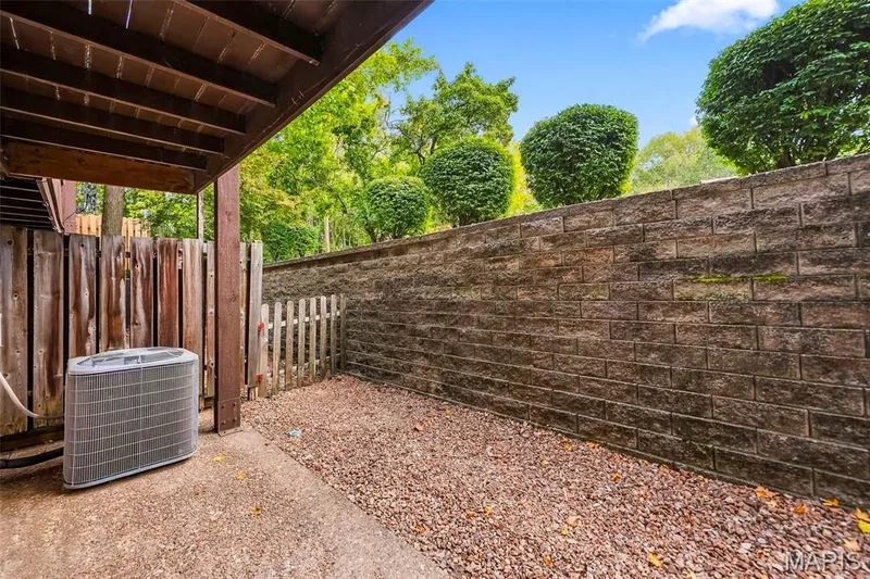 Lower level patio with a concrete surface, gravel hardscaping, and a retaining wall — 1410 Heritage Landing #106, St Charles, MO 63303