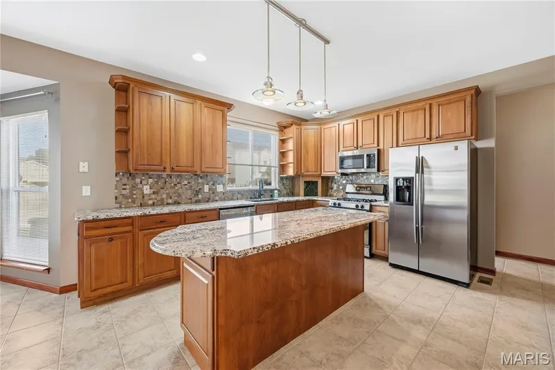 Large center island with breakfast bar, granite, custom tile backsplash and stainless appliances — 28 Wolverton Court, St Charles, MO 63301