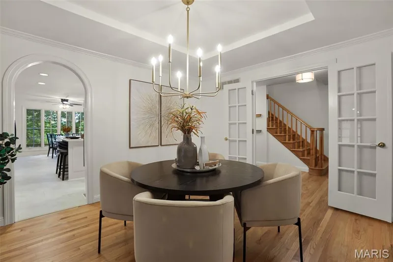 Tray ceiling with brass candelabra chandelier, arched entryway, wood-finish flooring, and multi-pane glass doors — 229 Quail Run Drive, Defiance, MO 63341