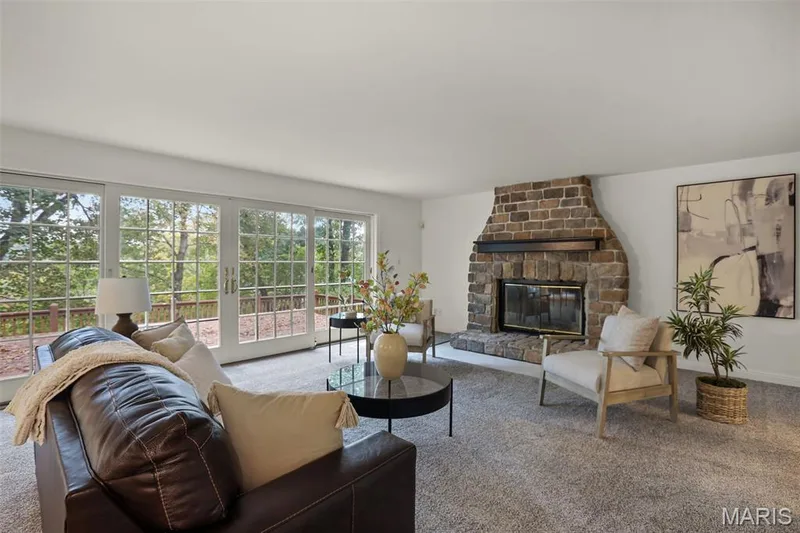 Floor-to-ceiling multi-panel sliding glass doors with grid detailing, and a floor-to-ceiling natural stone fireplace featuring a dark wood mantel — 229 Quail Run Drive, Defiance, MO 63341