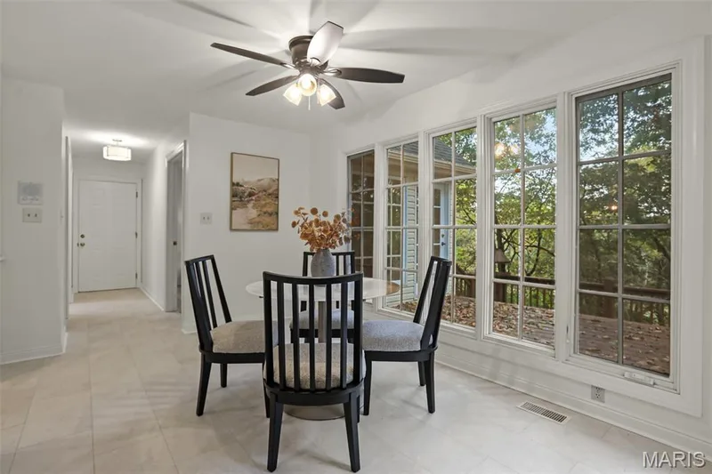 Large multi-pane windows, neutral tile flooring, and a ceiling fan with integrated lighting — 229 Quail Run Drive, Defiance, MO 63341
