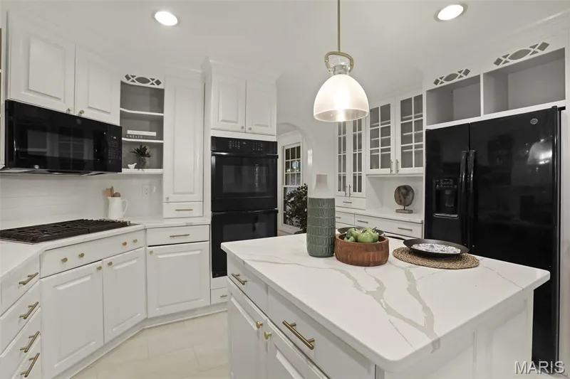 Kitchen featuring white cabinetry with glass-front display uppers, center island with stone-finish countertop, dual wall ovens, and recessed lighting — 229 Quail Run Drive, Defiance, MO 63341