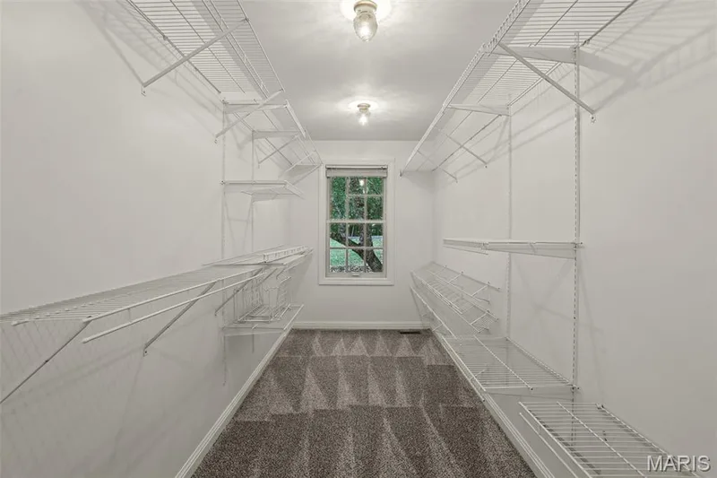 Walk-in closet featuring wall-to-wall carpeting, multi-level white wire shelving, and a single-hung window with natural lighting — 229 Quail Run Drive, Defiance, MO 63341