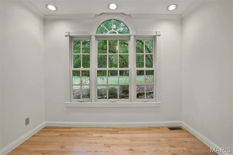 Triple-pane window assembly featuring a central arched transom, muntin grid detailing, recessed ceiling lighting, and wood-finish flooring — 229 Quail Run Drive, Defiance, MO 63341