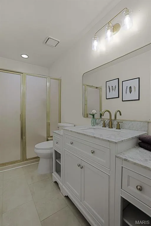 White vanity with stone-finish countertop, undermount sink, metallic hardware, three-light vanity fixture, and enclosed shower with metallic framing — 229 Quail Run Drive, Defiance, MO 63341