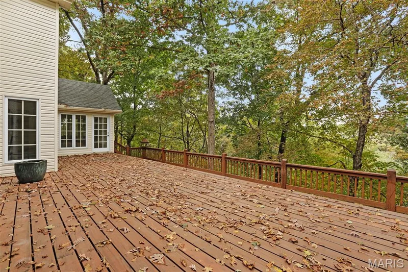 Expansive wood deck featuring a balustrade railing and mature trees — 229 Quail Run Drive, Defiance, MO 63341