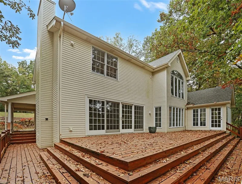 Multi-level wood deck featuring tiered stairs, siding exterior, sliding glass doors, and large windows with grid detailing — 229 Quail Run Drive, Defiance, MO 63341