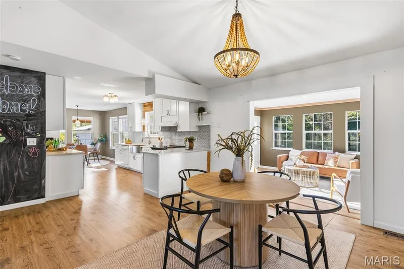 Vaulted ceiling featuring a beaded wood-frame chandelier, white cabinetry, wood-finish flooring, and a floor-to-ceiling chalkboard wall — 10341 Rose Lane, Foristell, MO 63348