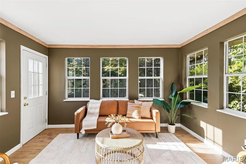Sun-filled room featuring multi-pane windows, wood-finish flooring, and natural wood crown molding — 10341 Rose Lane, Foristell, MO 63348