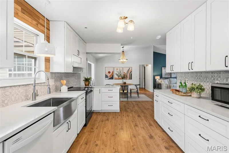 Kitchen featuring white shaker cabinetry, quartz countertops, patterned tile backsplash, wood-finish flooring, and a stainless steel farmhouse sink — 10341 Rose Lane, Foristell, MO 63348
