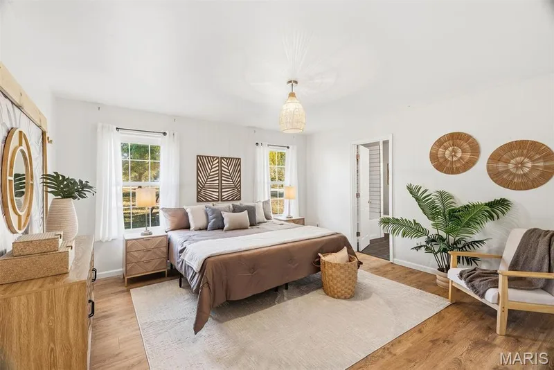Bright primary room featuring wood-finish flooring, two large windows, and a woven pendant light fixture — 10341 Rose Lane, Foristell, MO 63348